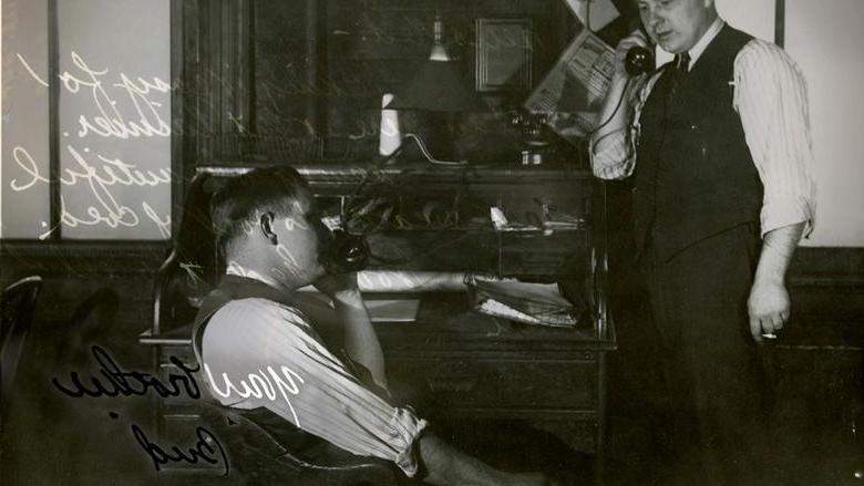 A black-and-white photo from September 9, 1942, shows two men in an office, each on the phone. The man on the left stands with a cigarette, while the man on the right is seated. The background features a cluttered desk. The image includes handwritten text and is signed Your brother, Bud.